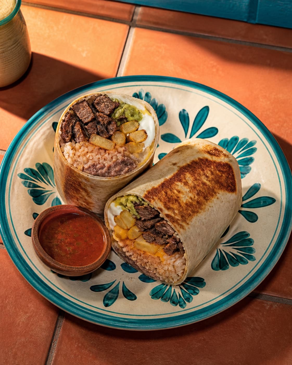 A California burrito cut in half with carne asada, fries, rice, beans, cheese, sour cream, and guacamole